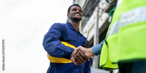 Focus hand African American Technician, Asian Engineer doing handshake together on white background. Group of Multi-Ethnic Blue-collar worker. Teamwork of Architect review plans at construction site