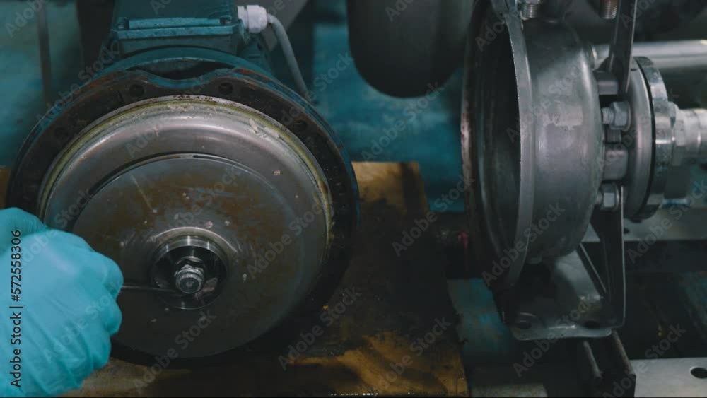A worker is cleaning white water pumps with stone chicken pallets