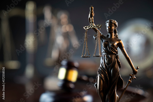 Law and justice concept. War crimes. Gavel and Themis sculpture in lawyers office. Gray bokeh background. photo