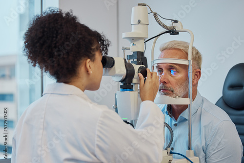 Vision, eye exam and healthcare with a doctor woman or optometrist testing the eyes of a man patient in a clinic. Hospital, medical or consulting with a female eyesight specialist and senior male photo