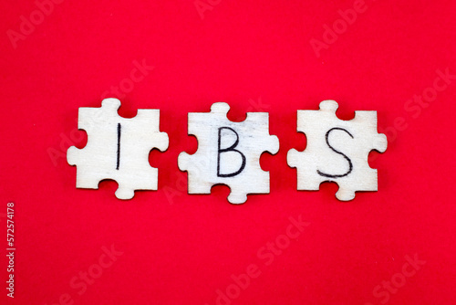 IBS Irritable Bowel Syndrome Acronym Written on Wooden Puzzles on a Red Background