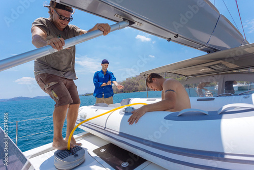 Three men with inflatable raft on sailboat, Lombok, Indonesia photo