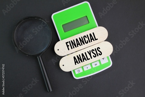 calculator, magnifying glass and wooden board with the word financial analysis