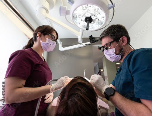 Dentist and and latin assistant examining a patient in dental clinic.