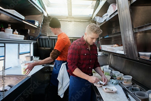 Two men preparing food inside concession stand photo