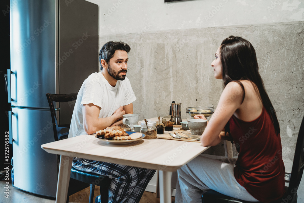 Young happy couple in love having breakfast at the kitchen table Young happy couple in love having breakfast at the kitchen table