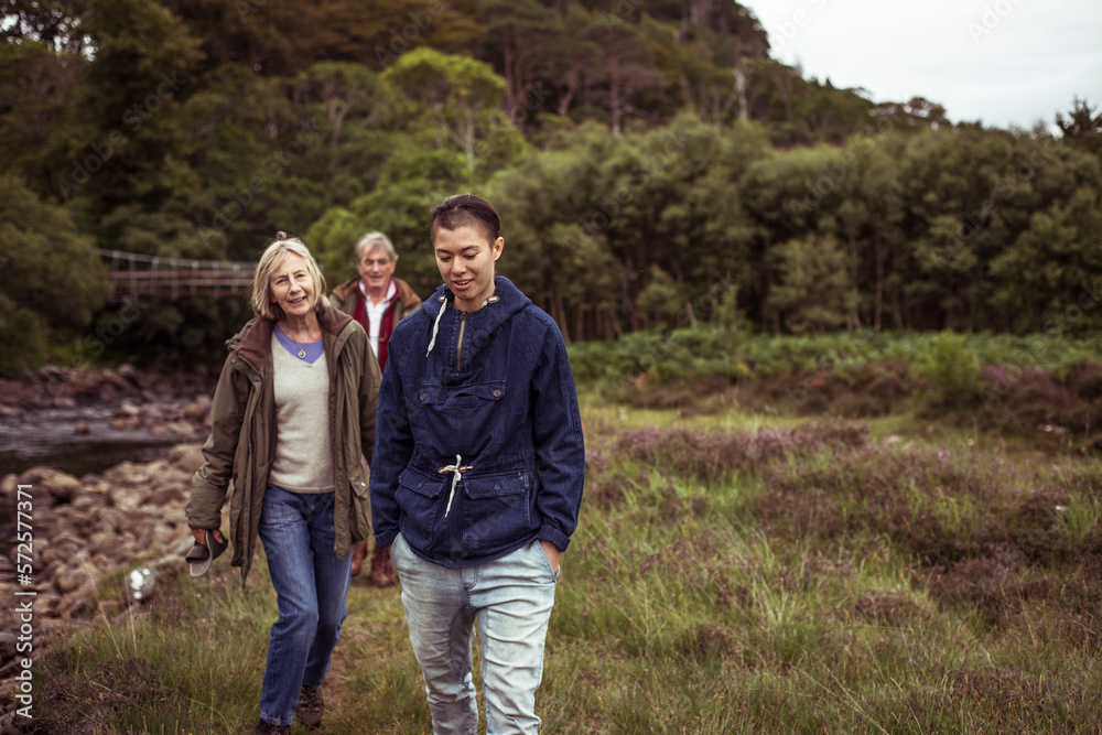 Mixed race older family walks along wild river grass Mixed race older family walks along wild river grass