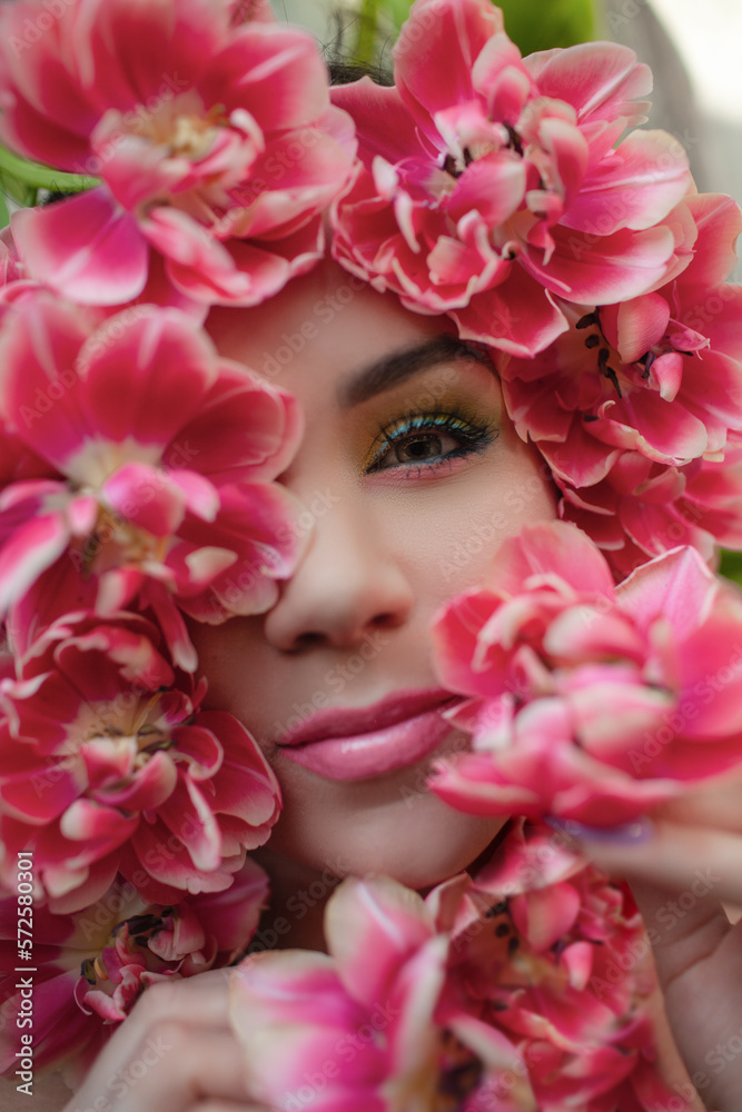 Portrait of a girl with good skin,perfume and cosmetics conceptThe face of beautiful woman with colorful make-up and flowers . The attractive woman lies in tulips.