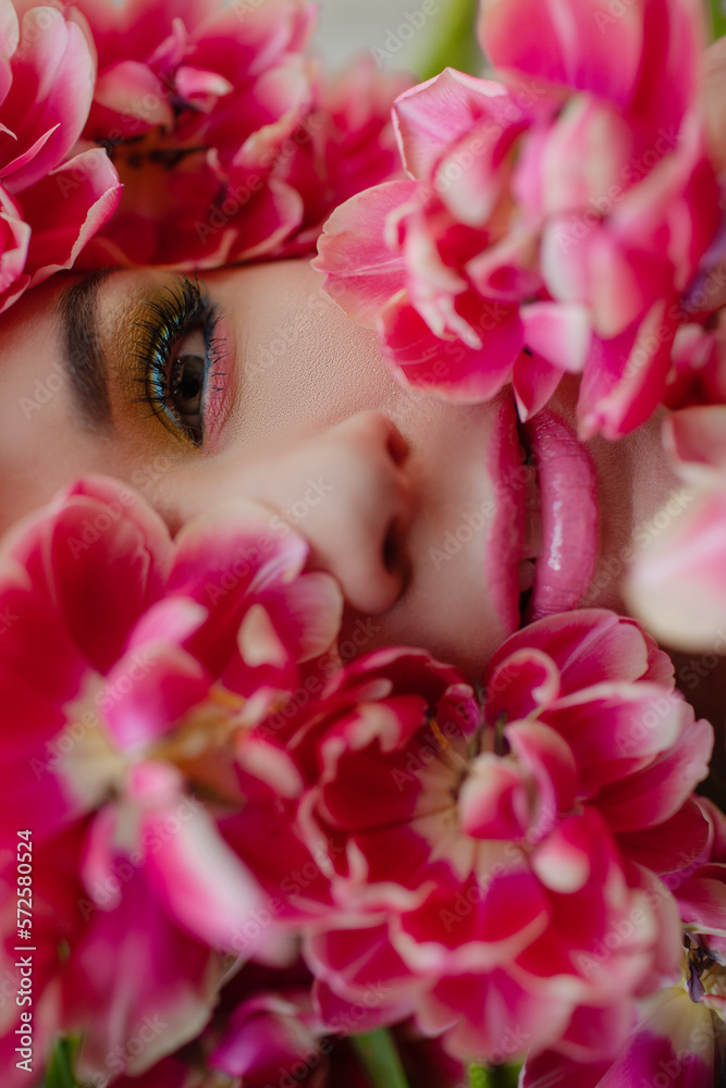 The face of beautiful woman with colorful make-up and flowers . The attractive woman lies in tulips. The face of beautiful woman with colorful make-up and flowers . The attractive woman lies in tulips.