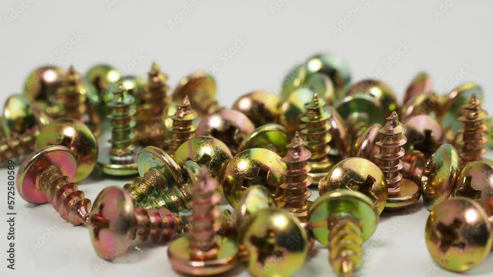 Metal screws on a white background. Rotating screws for driving into plastic. Close-up. Metal screws on a white background. Rotating screws for driving into plastic. Close-up.