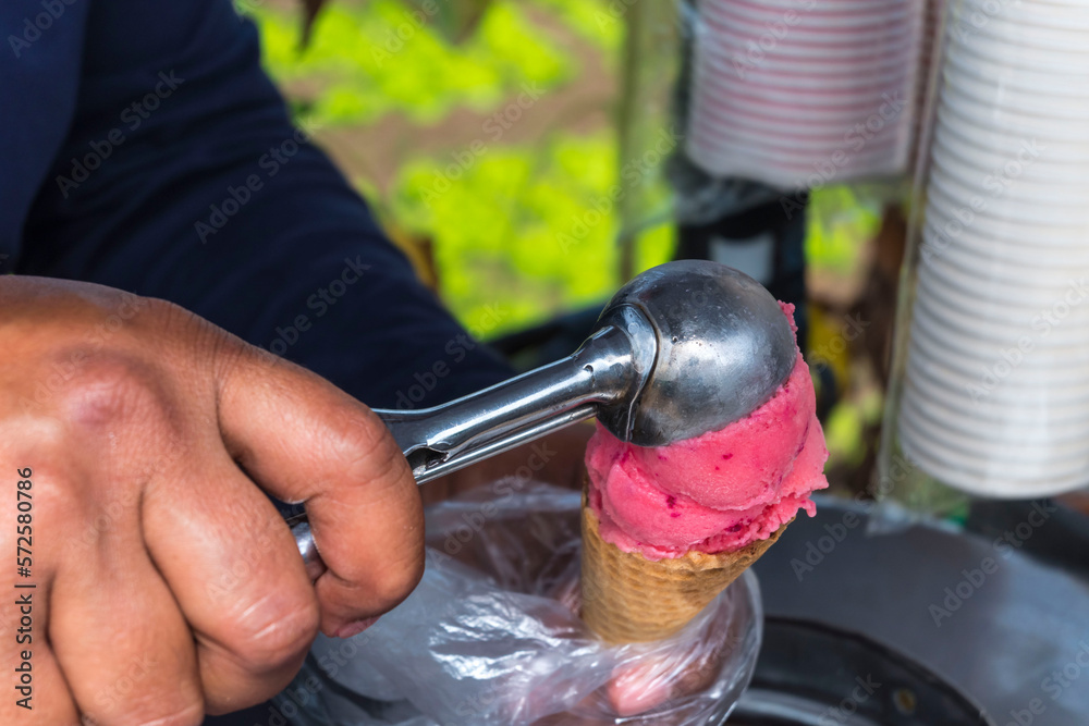 A vendor scoops homemade natural strawberry ice cream. A delicacy in La