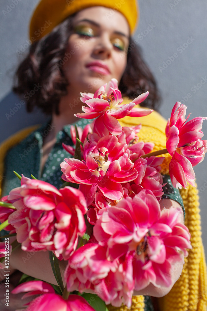 Portrait of a beautiful woman walks sround the city and holds a bouquet of pink flowers