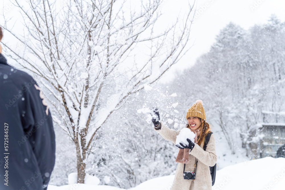 Asian couple have fun playing snow during travel small town and forest mountain together on winter holiday vacation. Man and woman enjoy outdoor lifestyle travel local village in Japan in snowy day.