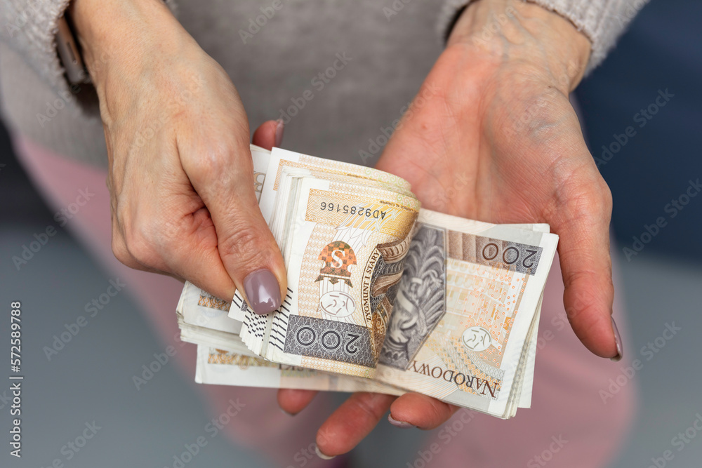 Kobieta trzyma w dłoniach banknoty, pieniądze polskie, złotówki. Liczenie pieniędzy. - obrazy, fototapety, plakaty 
