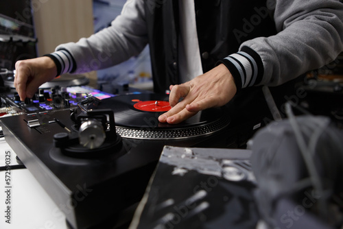 Hip hop dj scratching vinyl record with music on turntable player in close up