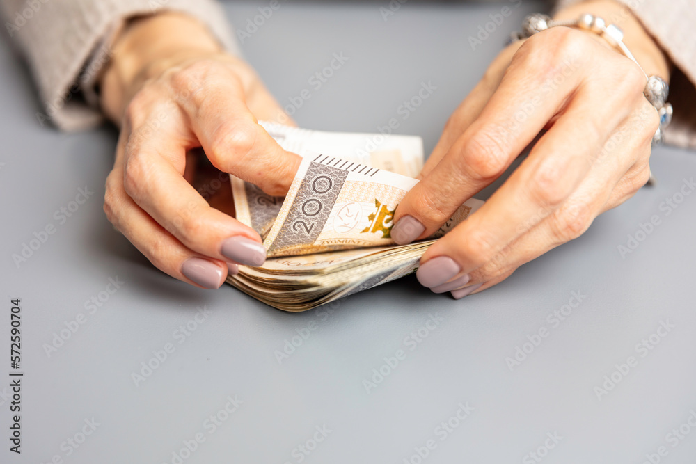 Kobieta trzyma w dłoniach banknoty, pieniądze polskie, złotówki. Liczenie pieniędzy. - obrazy, fototapety, plakaty 