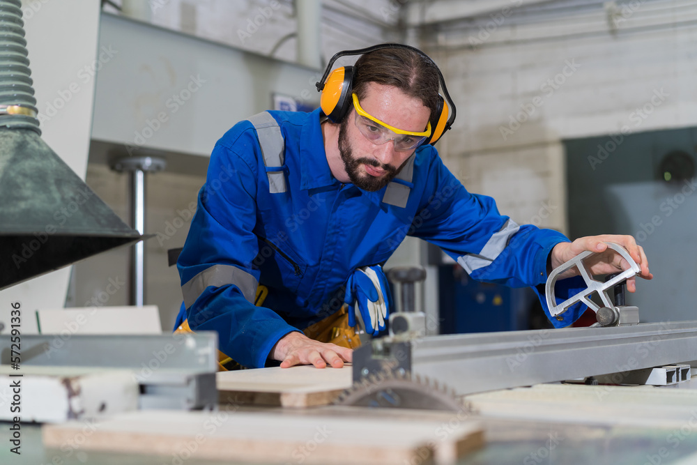 Male carpenter working with electronic saw machine for cutting wood plank at factory workshop. Production line of the wooden factory. CNC automatic woodworking machine in manufacturing industry Stock Photo | Adobe Stock
