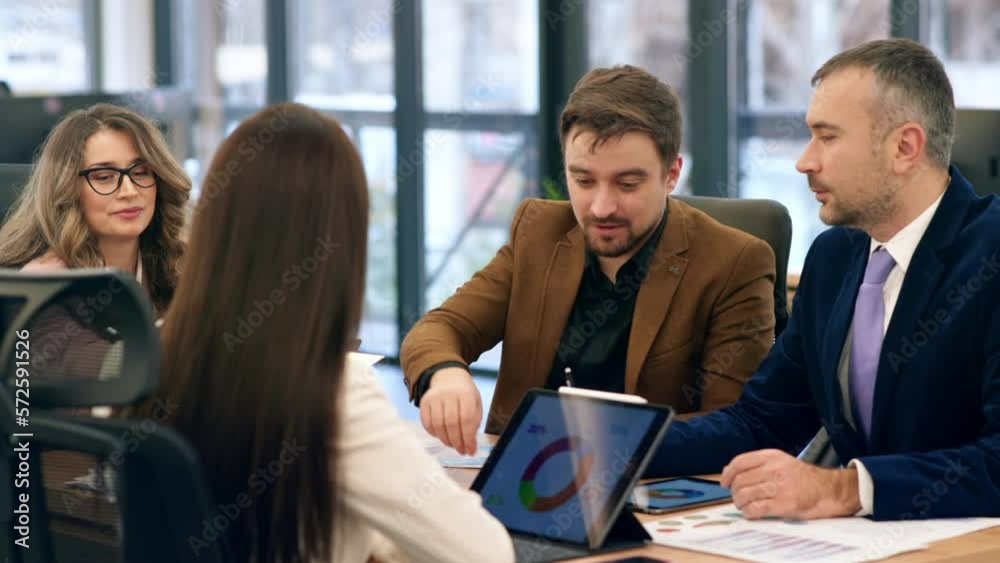 Business meeting in an office, workers discussing business affairs. Gadgets and papers with charts on the table Business meeting in an office, workers discussing business affairs. Gadgets and papers with charts on the table