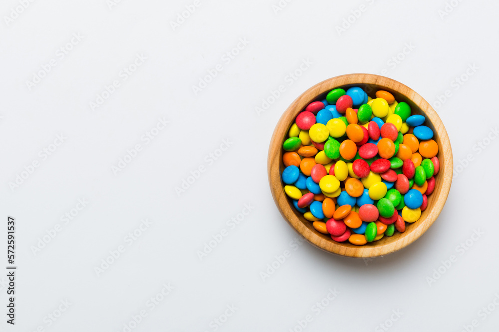 Multicolored candies in a bowl on a colored background. birthday and holiday concept. Top view with copy space