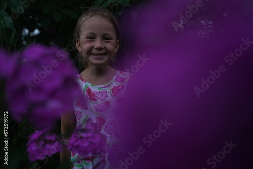 Cute girl child model in the garden between flowers at sunset. Selective focus © Oksana