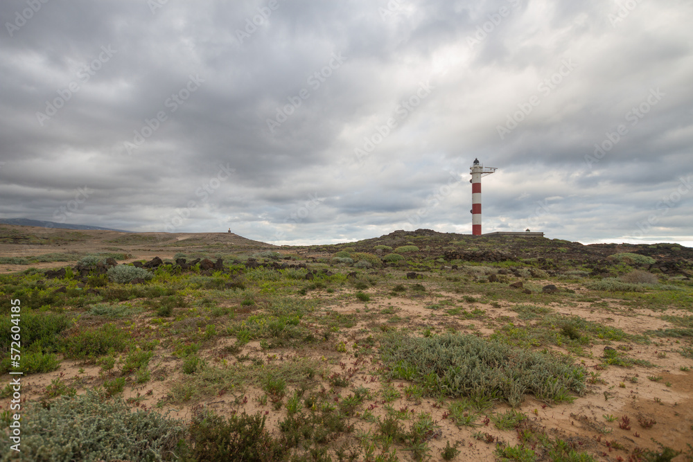 Desert landscape with volcanic rocks, lighthouse and storm clouds. Aabdes, Tenerife, Canary Islands. Spain