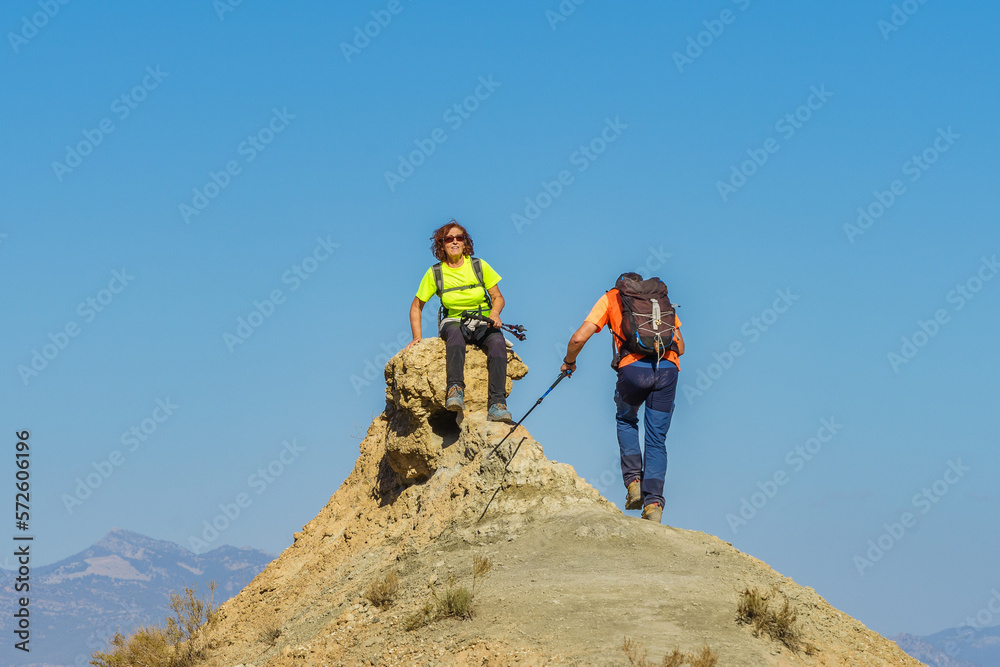 A hiker sitting at the top of the mountain awaits the arrival of her companion.