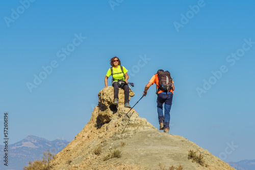A hiker sitting at the top of the mountain awaits the arrival of her companion.