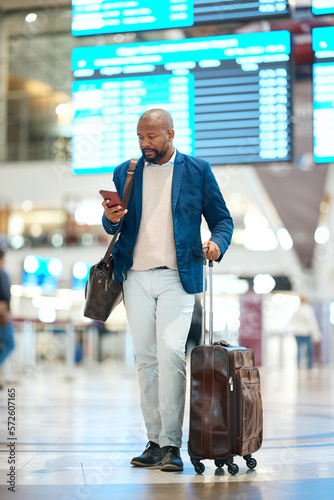 Black man with phone, luggage and checking flight schedule online, waiting in terminal for international business trip. Internet, travel app and businessman at airport for international destination.