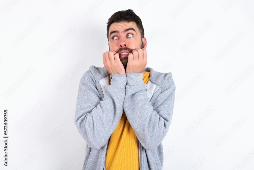 Terrified caucasian man wearing casual sportswear over white wall looks empty space home alone moonless night Terrified caucasian man wearing casual sportswear over white wall looks empty space home alone moonless night