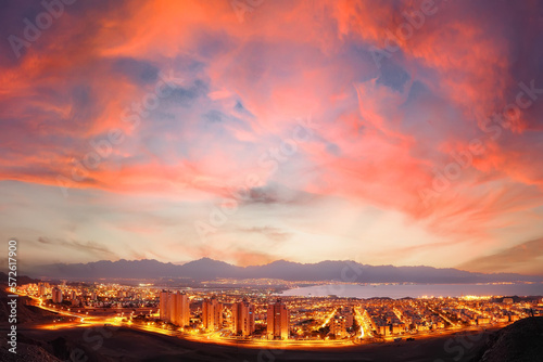 Sunrise panoramic view of Eilat. Israel. Glowing town lights at night. Red Sea. Lights of Aqaba, Jordan city on the opposite side of the bay (gulf). Jordan mountains in the in the foggy distance