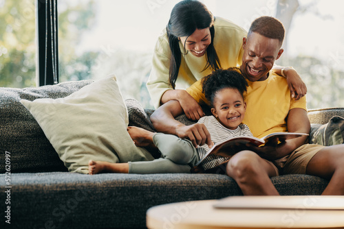 Happy little girl reading a story with her mom and dad