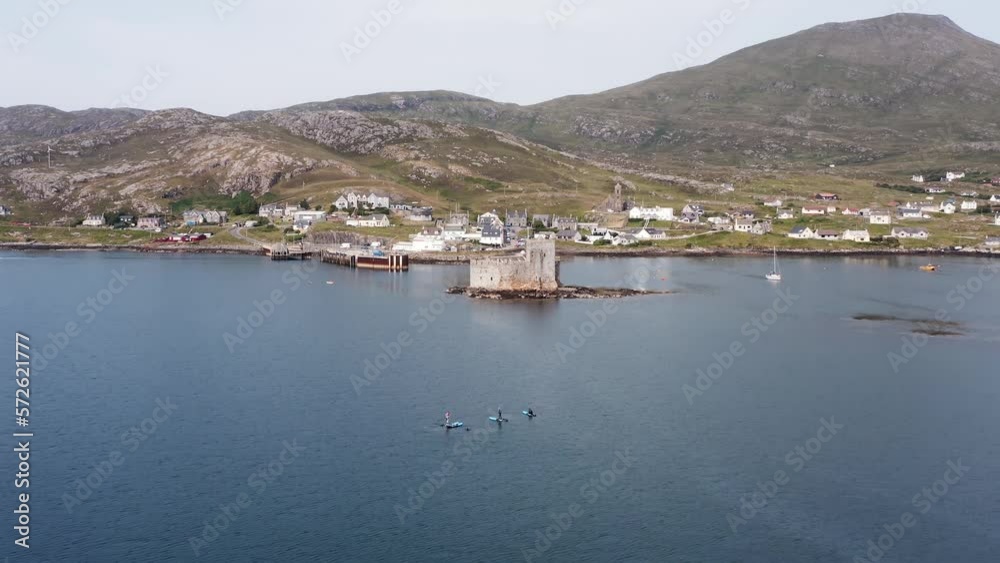 Drone shot of featuring paddle boarders. Shot includes Kisimul castle in Castlebay on the Isle of Barra in the Outer Hebrides of Scotland. Drone shot of featuring paddle boarders. Shot includes Kisimul castle in Castlebay on the Isle of Barra in the Outer Hebrides of Scotland.