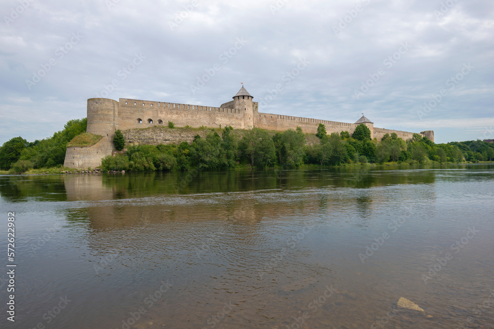 View of the ancient Ivangorod fortress from the side of the Narva river on a cloudy August morning. Border of Estonia and Russia