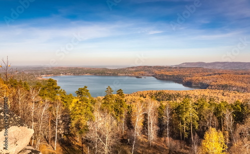 Autumn landscape from the top of a mountain with a lake, trees, mountains and sky