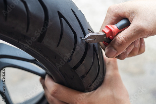 Obraz na płótnie screw nail or Iron stuck puncturing motorcycle or scooter tire,mechanic repair a tire puncture from a nail or screw at motorcycle repair shop.motorcycle repair and maintenance concept w salonie
