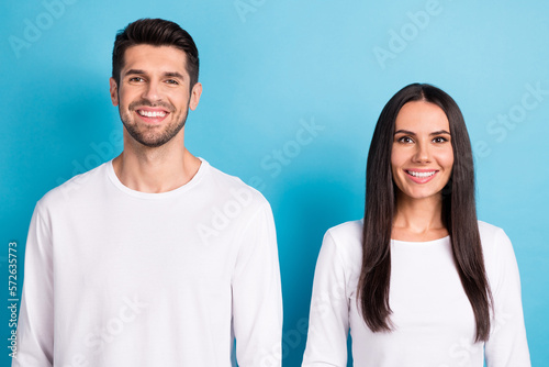 Photo portrait of cute young man woman toothy beaming smile promo workers dressed stylish white clothes isolated on blue color background