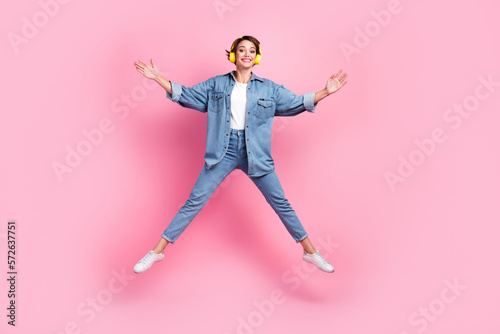 Full length photo of sweet impressed lady dressed denim jacket listening songs jumping high like star isolated pink color background