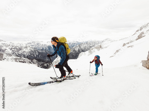 Adventurous couple ski touring high up in the snowy Alps on a beautiful winter day