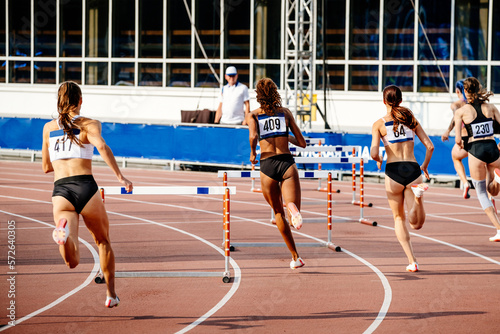 women running 400 - meter hurdles in athletics competition photo