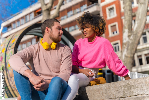 Multiracial couple on the city streets, lifestyle, sitting looking at each other and smiling