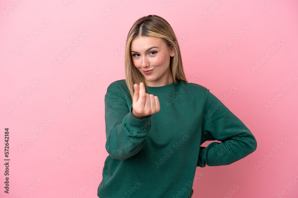 Young caucasian woman isolated on pink background making money gesture