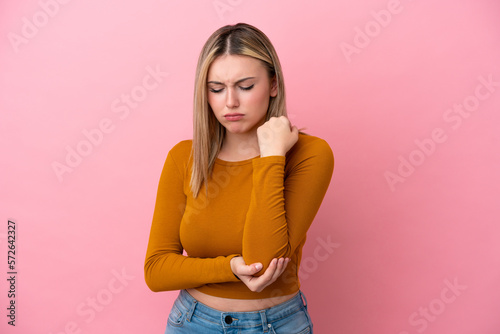 Young caucasian woman isolated on pink background with pain in elbow © luismolinero