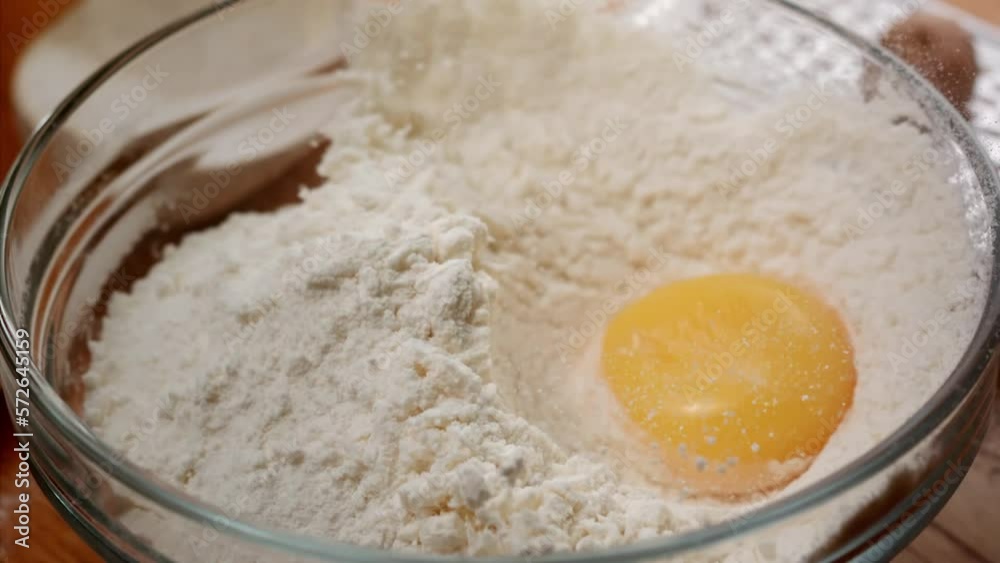 macro shot of a kitchen whisk breaking a yellow egg in flour in ultra slow motion macro shot of a kitchen whisk breaking a yellow egg in flour in ultra slow motion