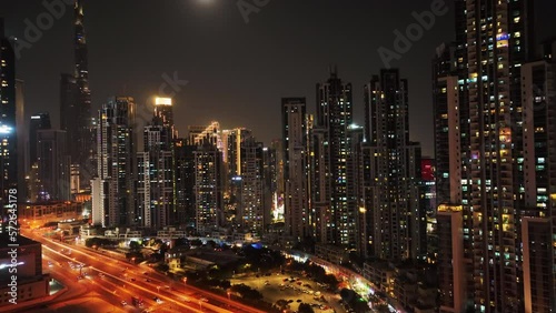 Cinematic aerial shot of Downtown Dubai iconic skyline buildings, world's tallest Burj Khalifa, Sheikh Zayed Road, luxury hotels and properties illuminated with night light	