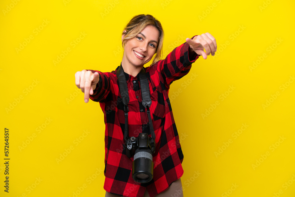 Uruguayan photographer woman isolated on yellow background points finger at you while smiling Uruguayan photographer woman isolated on yellow background points finger at you while smiling