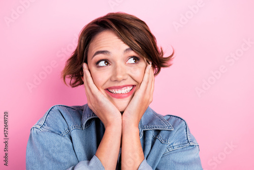 Portrait of adorable cheerful person arms touch cheeks beaming smile look empty space isolated on pink color background