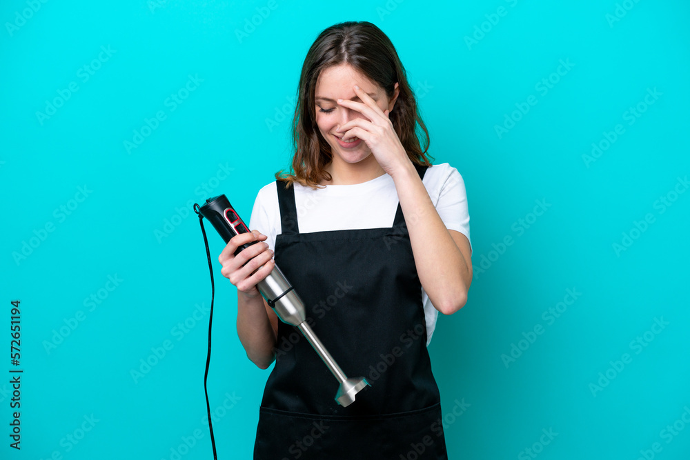 Young caucasian cooker woman using hand blender isolated on blue background laughing Young caucasian cooker woman using hand blender isolated on blue background laughing