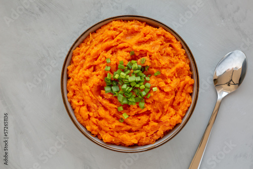 Homemade Creamy Mashed Sweet Potatoes with MIlk and Butter in a Bowl on a gray background, top view.