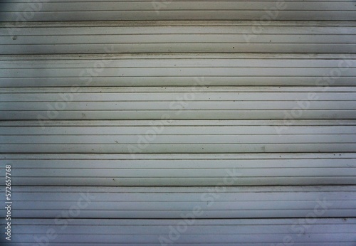 Grauweiß gestreifte geschlossene Jalousie vor Fenster als Hintergrund 