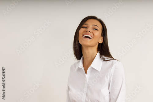 Obraz na plátně Portrait of happy laughing brunette girl dressed in white shirt